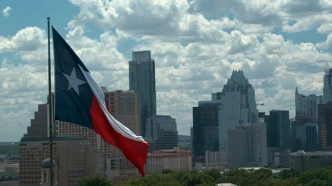 Texas Flag, aerial camera orbits left with Capital and Austin in the back, 4K 스톡 동영상 111067730