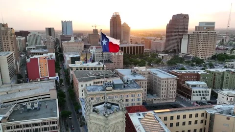 Texas flag over San Antonio skyline at sunset. Aerial view in slow motion. Stock Footage 200374892
