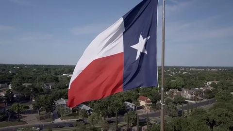 Texas Flag Waving while aerial camera orbits with downtown Austin in the back Stock Footage