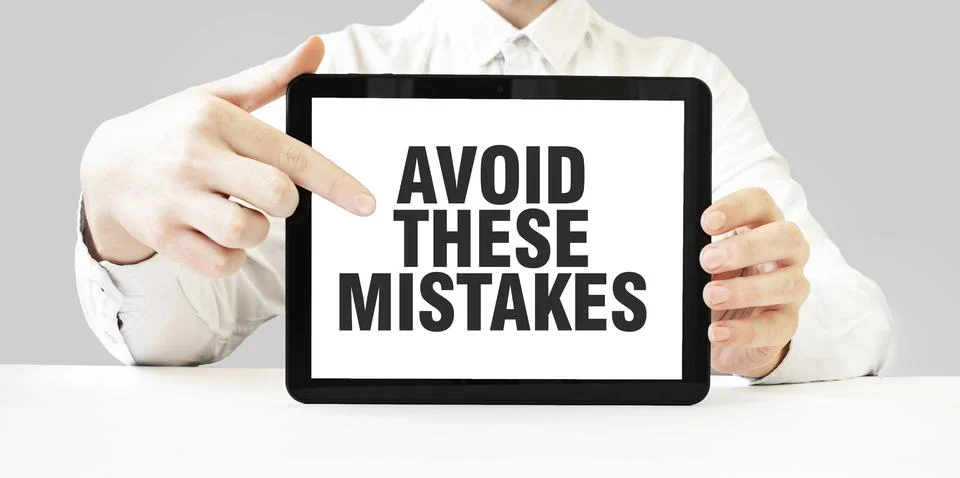 Text AVOID THESE MISTAKES on tablet display in businessman hands on the whi.. Foto stock