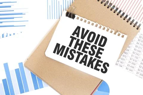 Text AVOID THESE MISTAKES on white paper sheet and brown paper notepad on t.. Foto stock