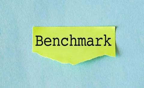 Text Benchmarking appearing behind torn yellow paper on blue background Stock-Fotos