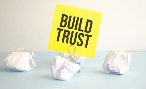 The text BUILD TRUST appearing behind torn white paper Stock Photos
