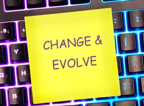 The text CHANGE EVOLVE written on a yellow sticker on a bright keyboard backg Stock Photos