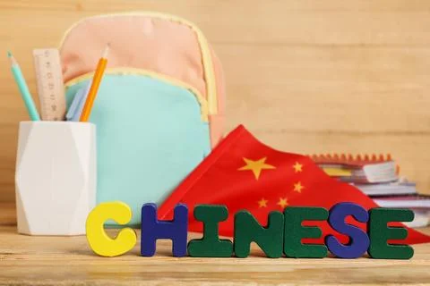 Text CHINESE with flag, backpack and stationery on wooden background Stock Photos