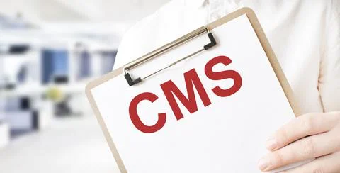 Text CMS on white paper plate in businessman hands in office. Business concep Stock Photos