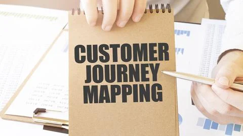 Text CUSTOMER JOURNEY MAPPING on brown paper notepad in businessman hands o.. Stock Photos
