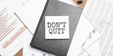 Text Dont Quit on notepad with office tools, pen on financial report . Busine Stock Photos