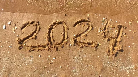 Text figures 2024 handwritten numbers by tourists on golden sandy beach surface, Stock Footage 278463272