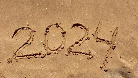 Text figures 2024 handwritten numbers by tourists on golden sandy beach surface, Video stock 284439928
