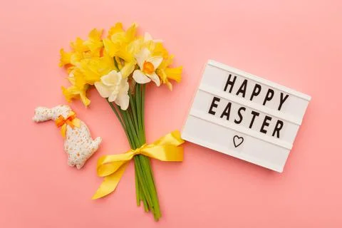 Text Happy Easter, light yellow spring bouquet and easter bunny on pink Stock Photos