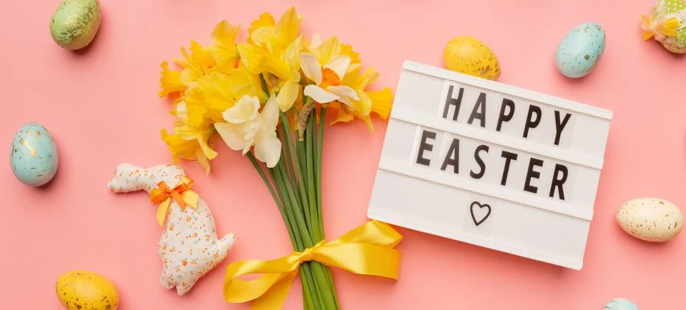 Text Happy Easter, light yellow spring bouquet and easter decor on pink Stock Photos