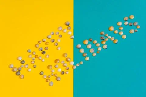 Text "Happy Holidays" made of small seashells on yellow and blue paper backgr Stock Photos