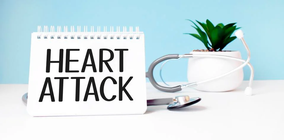 The text HEART ATTACK is written on notepad near a stethoscope on a blue back Stock Photos