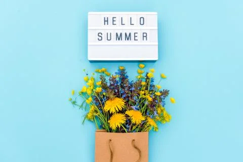 Text Hello Summer on light box and bright bouquet of wildflowers in craft pac Stock Photos