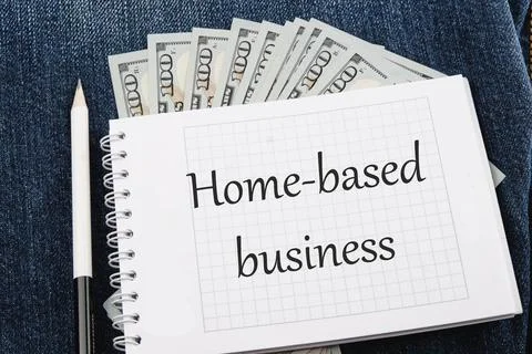 Text Home based business on a notebook lying on jeans with dollar bills Stock Photos