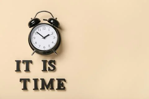 Text IT IS TIME with alarm clock on beige background Stock Photos