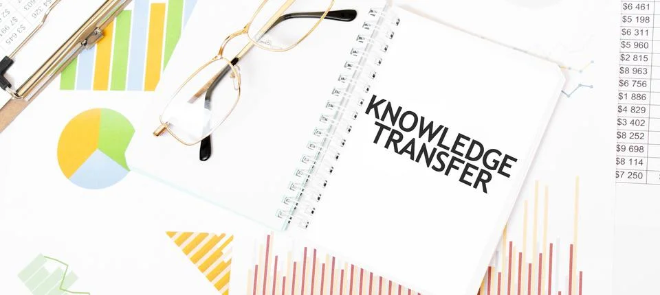 Text KNOWLEDGE TRANSFER. on white notepad, glasses, graphs and diagrams. Stock Photos