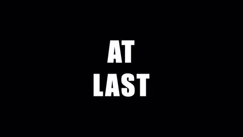 Text AT LAST appears with changing color and animation during a dark cinema.. Video stock 344283639