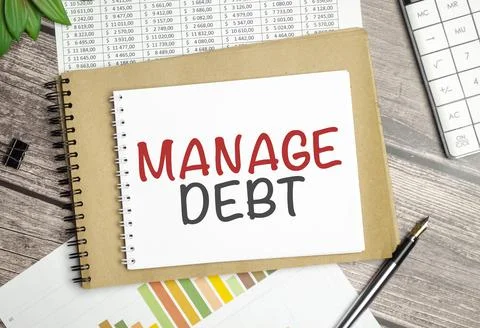 Text Manage Debt on notepad and pen on wooden background Stock Photos