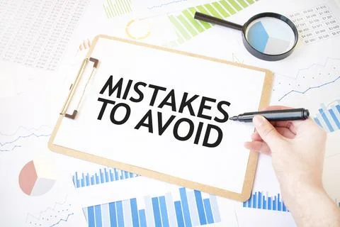 Text MISTAKES TO AVOID on white paper sheet and marker on businessman hand .. Stockfoto's