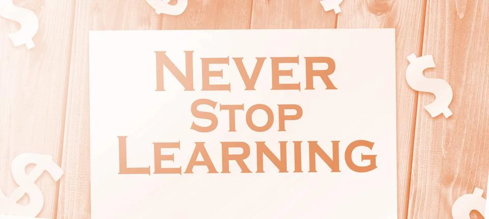 Text never stop learning on page, dollar signs on wood table. education conce Stock Photos