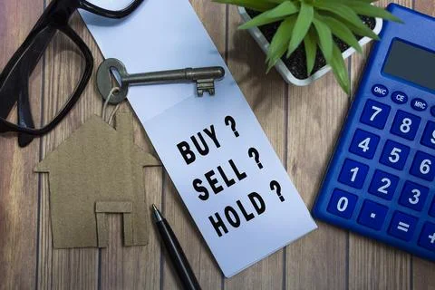 Text on notepad with house model and key on wooden desk. Investment concept. Stock Photos