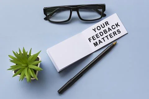 Text on notepad with reading glasses and potted plant on blue background Stock Photos