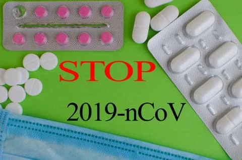 Text phrase Coronavirus on a green background with medicines and protective m Stock Photos