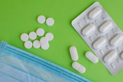 Text phrase Coronavirus on a green background with medicines and protective m Stock Photos