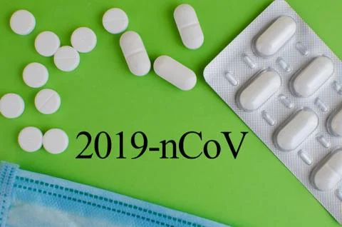 Text phrase Coronavirus on a green background with medicines and protective m Stock Photos