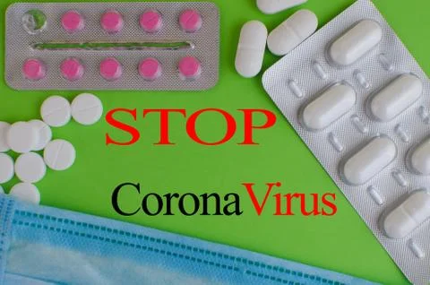 Text phrase Coronavirus on a green background with medicines and protective m Stock Photos