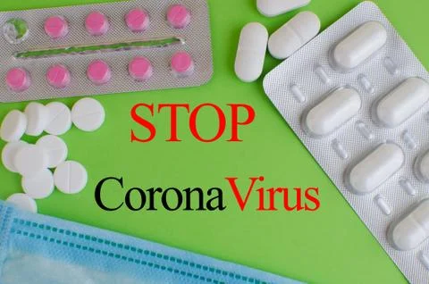 Text phrase Coronavirus on a green background with medicines and protective m Stock Photos