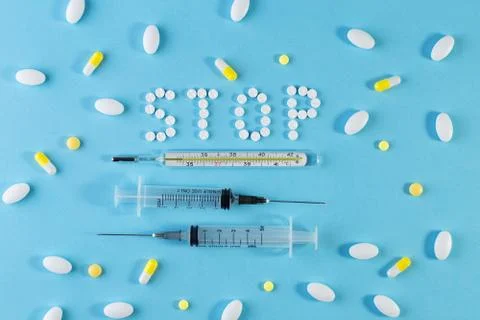 Text phrase STOP on a blue background with pills. Stock Photos