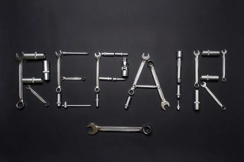 Text REPAIR made of tool set on black background. Mechanic tools, wrenches or Stock Photos