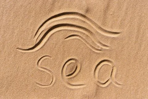 The text "Sea" is handwritten on a golden sandy beach near the sea Stock Photos
