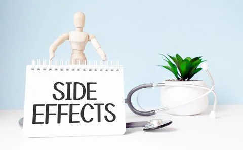 The text SIDE EFFECTS is written on notepad and wood man toy near a stethosco Stock Photos