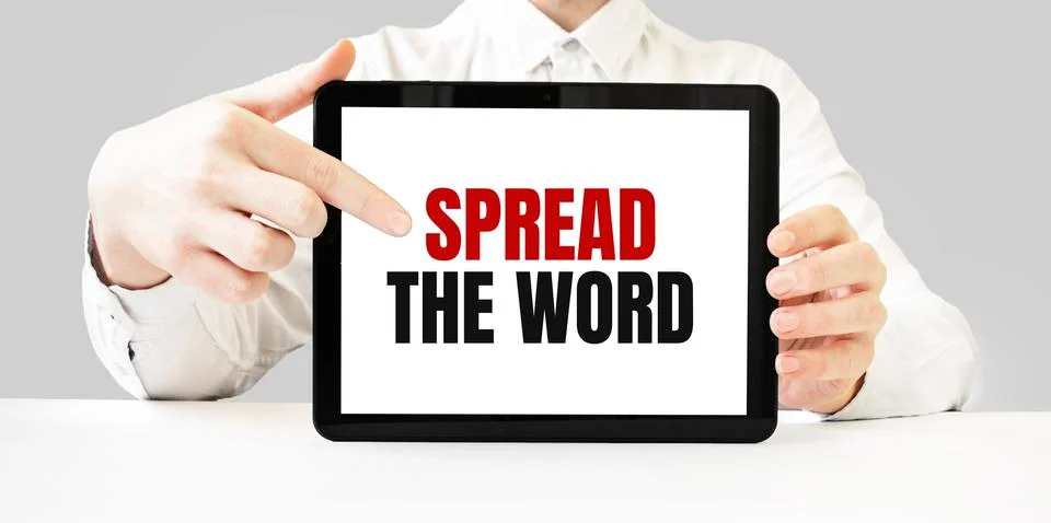 Text SPREAD THE WORD on tablet display in businessman hands on the white bakc Stock Photos