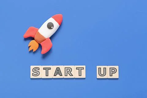 Text START UP with paper rocket on blue background Stock Photos