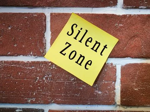 Text on sticky yellow note on brick wall. Silent zone Stock Photos