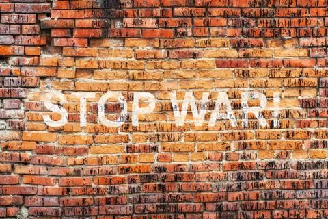 Text STOP WAR on stained old orange brick wall texture background Stock Photos
