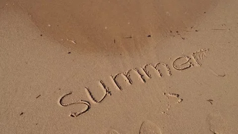 Text SUMMER handwritten in sand surface. Blue ocean wave washing away message at Stock Footage 243241157
