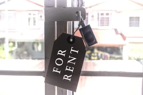 Text on tag hanging on the window grill with blurred background of houses Stock Photos