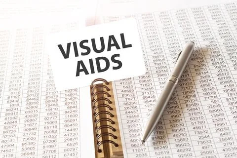 Text VISUAL AIDS on paper card, pen, financial documentation on table - bus.. Stock Photos