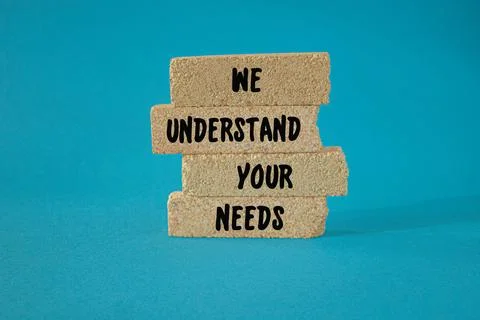 Text WE UNDERSTAND YOUR NEEDS on brick blocks. Beautiful blue background Foto stock