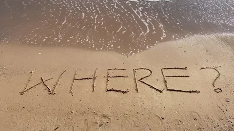 Text Where? handwritten in sand surface. Blue ocean wave washing away quest.. Stock Footage 251800736