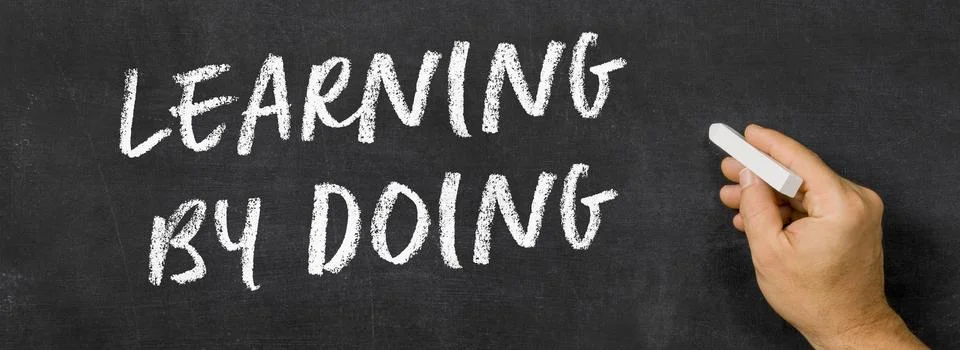 Text written on a blackboard -  Learning by doing Photos