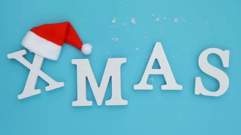 Text Xmas from white letters in red Santa hat and falling snow Stock Footage 112860275