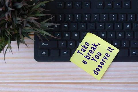 Text on yellow note with keyboard and potted plant on wooden table Stock Photos