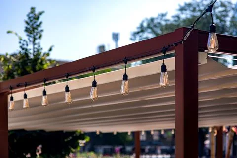 Textile awning in the backyard with a garland of strings. Stock Photos